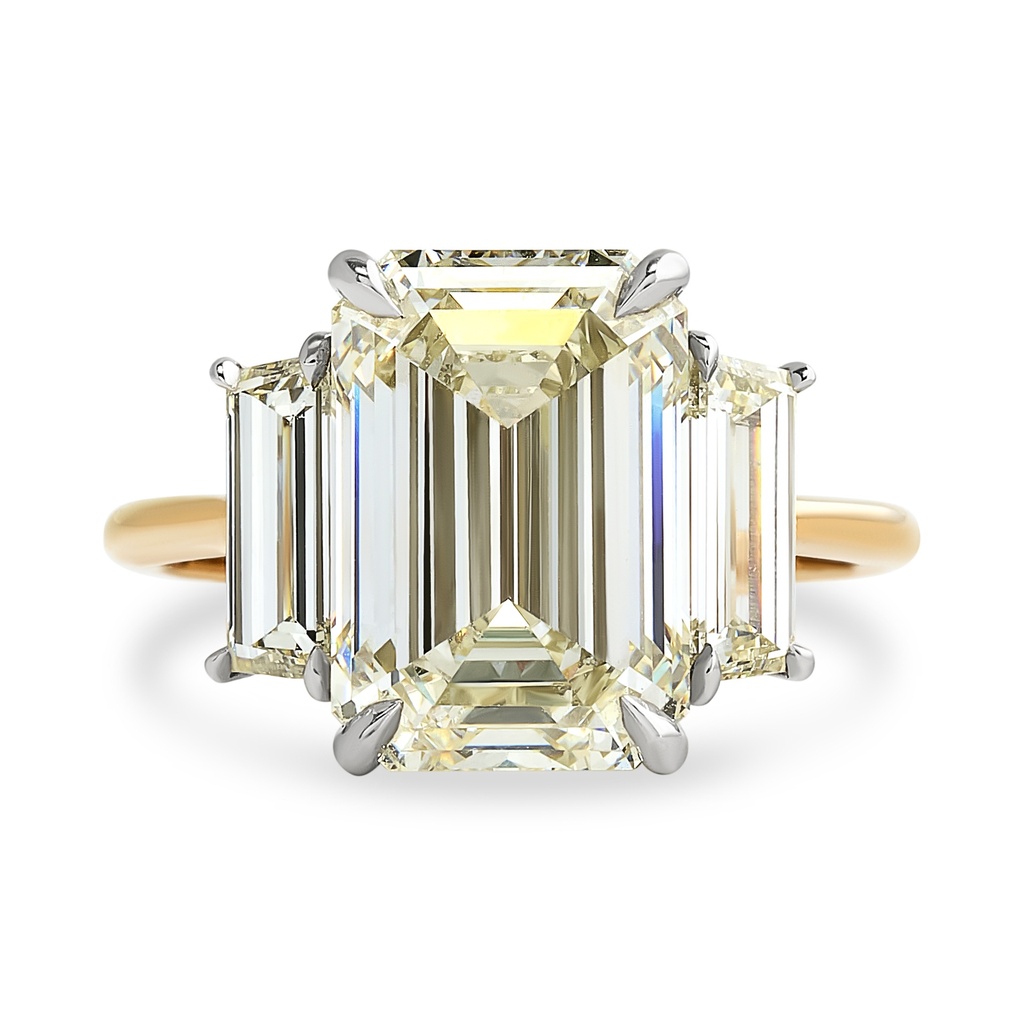 Platinum and 14Kt Yellow Gold Three Stone Ring With An Emerald Cut Diamond Weighing 5.02ct And (2) Tapered Step Cut Diamonds Weighing 0.96ct